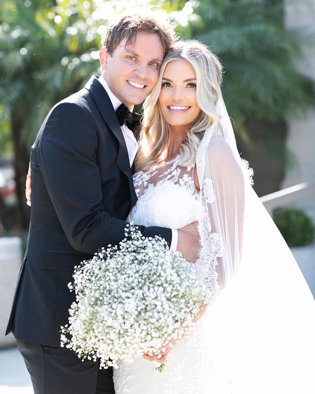 Lauren Wirkus in a white bridal dress and David Raih in a black formal suit at their wedding ceremony.